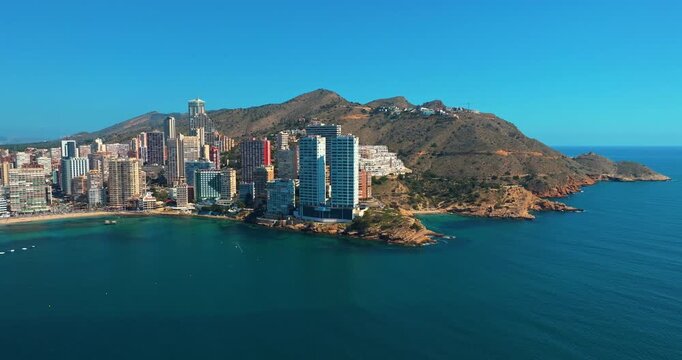 Aerial view of Benidorm skyline Spain in summer. Modern skyscrapers on the Mediterranean coast with mountains in the background. Drone shot of the famous holiday resort on a bright sunny day.