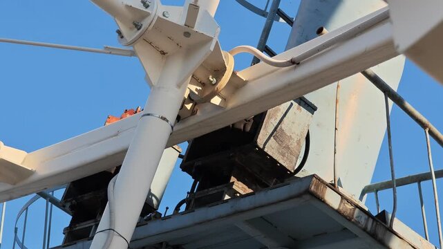 Detail shot of the inner workings and rusty gears of a large ferris wheel rotating. White metal beams and supports moving smoothly