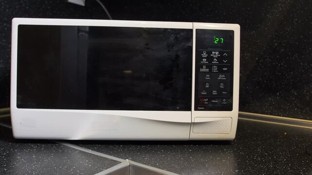 hand pressing microwave buttons close-up view, selecting cooking program on control panel display, setting timer and heating mode, kitchen appliance operation and everyday food preparation at home