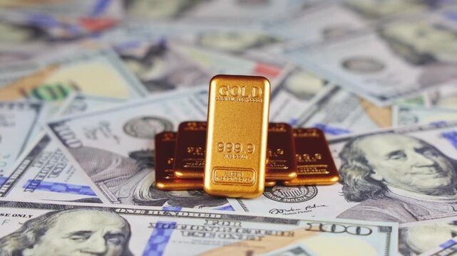 Gros plan sur des lingots d'or pos&eacute;es sur des billets en dollar. Concept de dollar vs or.