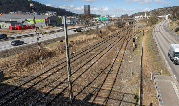 Gothenburg, Sweden - March 27 2026: Railway tracks and parallel road with light traffic in industrial outskirts.