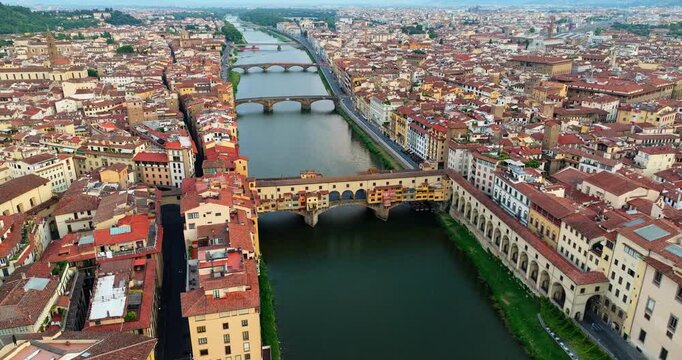 Aerial view iconic Ponte Vecchio bridge in Florence Italy. Historic stone architecture over Arno river captured by drone on a sunny summer day. Popular travel destination UNESCO heritage site.