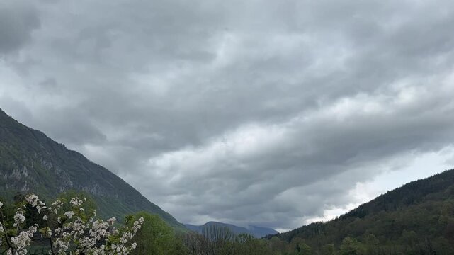 Time lapse of clouds drifting over green mountain landscape with rolling hills and forest. Dynamic sky and changing weather in natural environment. Scenic countryside view with atmospheric motion.