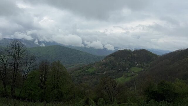 Time lapse of clouds drifting over green mountain landscape with rolling hills and forest. Dynamic sky and changing weather in natural environment. Scenic countryside view with atmospheric motion.