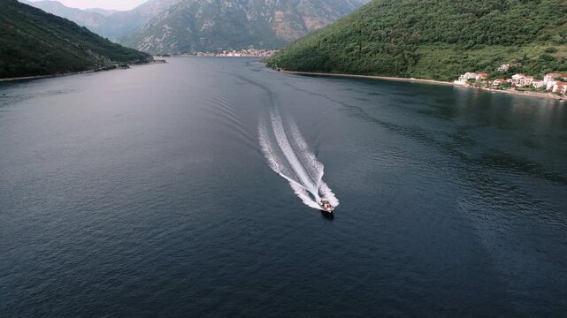 Maritime voyage over scenic coast. Aerial shot of man steering boat through picturesque coastlines and villages