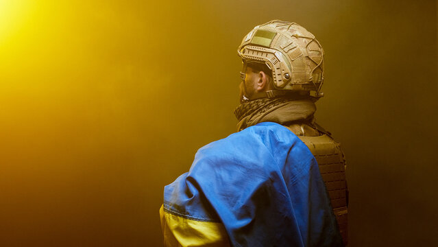 Soldier with Ukrainian flag in tactical gear, golden sunset lighting and strong visual mood. Concept national pride and unity.
