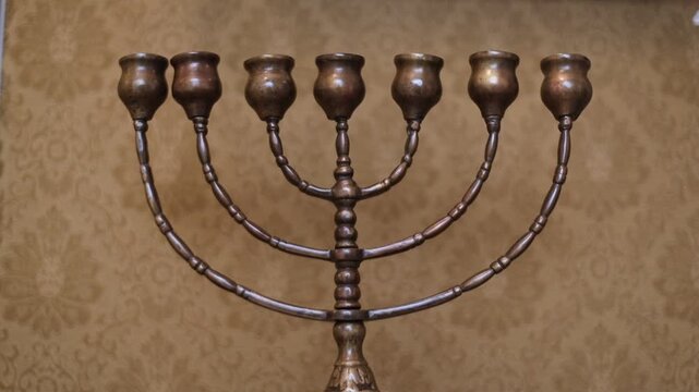 A decorative metal menorah with five lit candles, suitable for Hanukkah celebrations or Jewish cultural events
