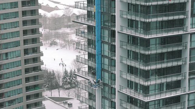 Urban cleaning scene. Efficient workers on highrise cleaning platform view snowy courtyard with sleek architecture