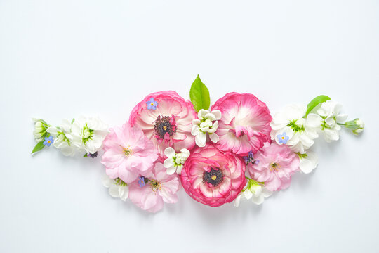 Flat lay floral arrangement with ranunculus, sakura and mattiola flowers in a symmetrical composition on a white background, top view, copy space, Mothers Day concept