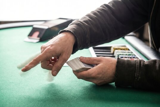 Casino dealer throwing playing card across green felt table during poker game