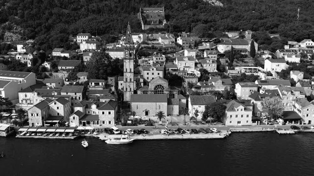 Coastal town with boats and hills. Serene picture of Perast harbor with historic buildings and lush surroundings