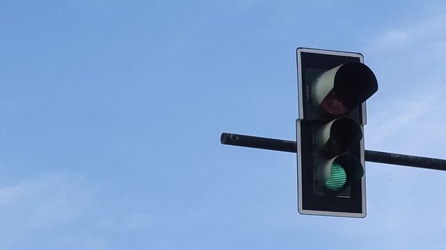 Traffic light changing from red to green against blue sky, signaling stop to go transition, road safety concept, urban infrastructure, transportation control system operation