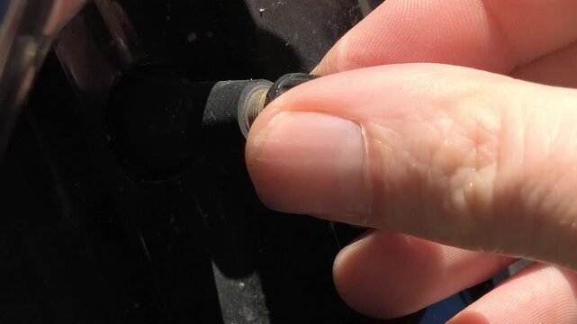 Close up of hand unscrewing valve cap on car tire, preparing to check or inflate wheel pressure, automotive maintenance detail, vehicle service and safety concept