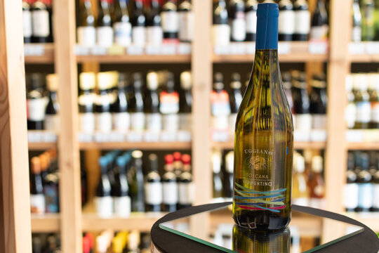 Bottle of Uggiano Vermentino Toscana IGT white wine on a mirror surface in a wine store with blurred shelves of various bottles in the background. Ukraine, Zhytomyr, April 28, 2026