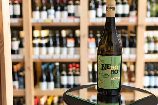 Bottle of Nero Oro Pinot Grigio Terre Siciliane Skin Contact white wine on a mirror surface in a wine store with blurred shelves in the background. Ukraine, Zhytomyr, April 28, 2026