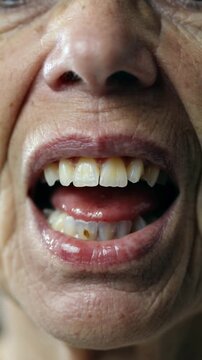 Mature woman mouth speaking, extreme close up showing natural teeth and aging skin texture