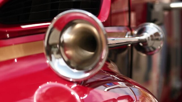 Detailed shot of a brightly polished bugle style horn attached to a classic red fire truck