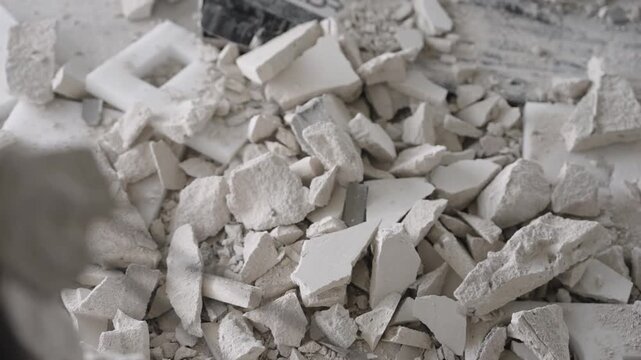 Close up of demolished building. Broken concrete with rusty steel rebar in sharp focus against blurred rubble background. Somber, monochromatic scene depicting destruction, decay, disaster aftermath