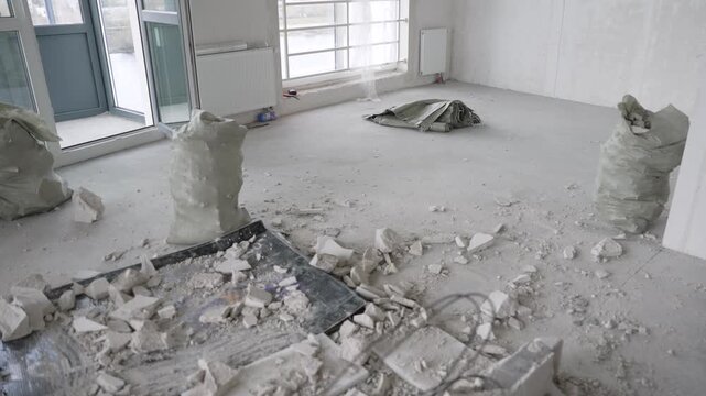 Messy apartment renovation with construction debris on concrete floor