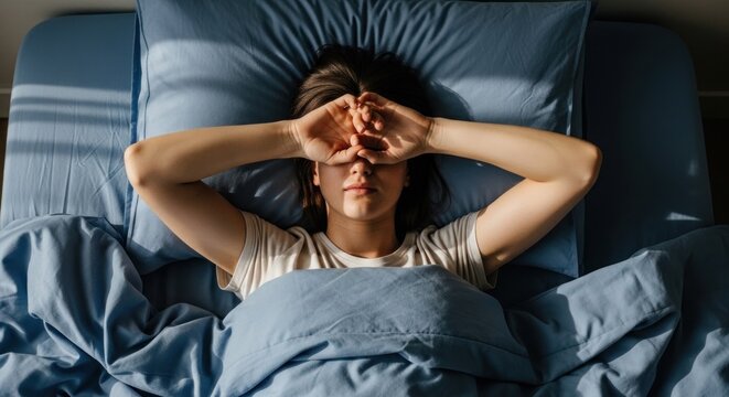 Person sleeping, eyes covered, bathed in sunlight from window