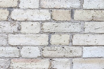 Obraz premium A close-up of a damaged exterior wall of a building with bricks erosion. Construction material and brown bricks. Background or backdrop with brown, white and beige colors.