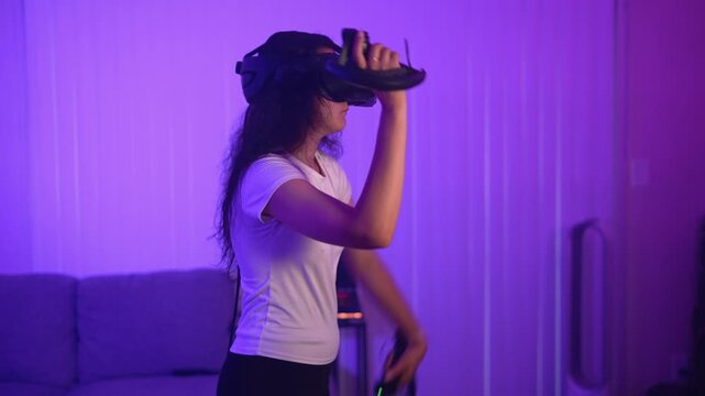 Woman playing virtual reality game with controllers indoors using modern technology for entertainment and immersive interactive digital experience
