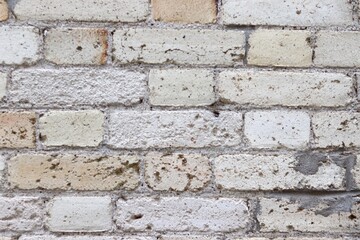 Fototapeta premium A close-up of a damaged exterior wall of a building with bricks erosion. Construction material and brown bricks. Background or backdrop with brown, white and beige colors.