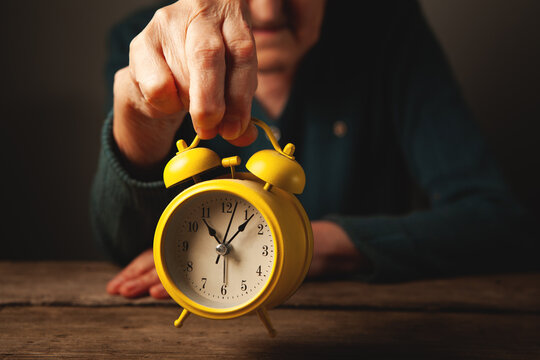 woman 's hands with a clock on a wooden table.