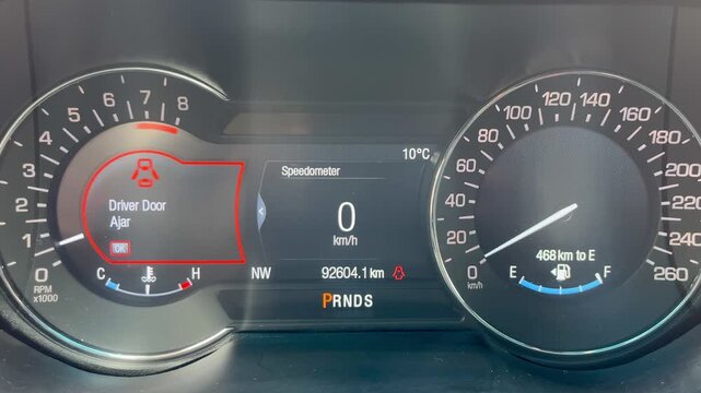 Digital car dashboard with red door-ajar warning signal.