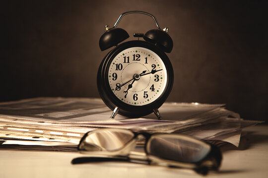 Alarm clock and eyeglasses on a desk in the office