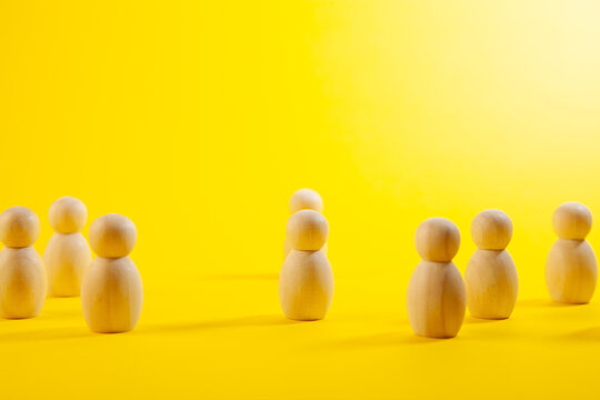 Wooden figures on a green background. The concept of teamwork and cooperation.