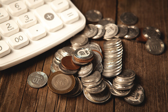 calculator and coins on wooden background.