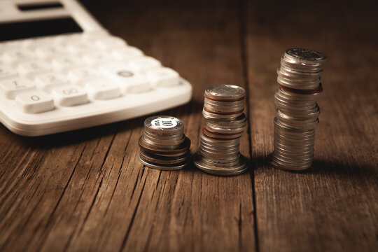 calculator and coins on wooden background.