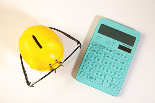 calculator with a yellow piggy bank and a toy house on a white background.