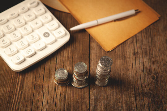 calculator and coins on wooden background.