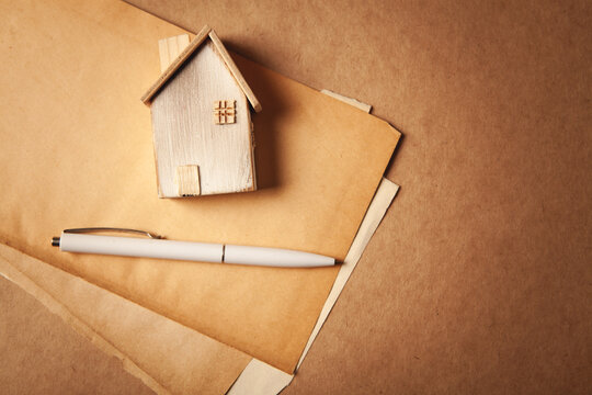 House model, pen and envelope on brown paper background with copy space