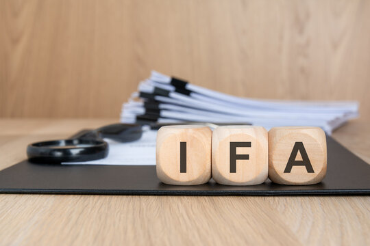 IFA text on wooden blocks with business documents and magnifying glass.