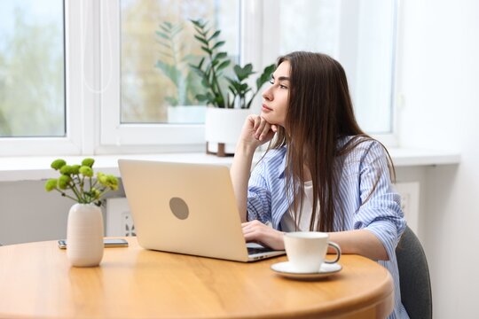 Young student studying with laptop at wooden table indoors