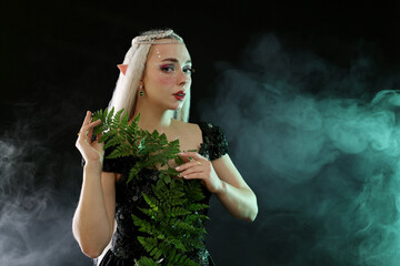 Naklejka premium Beautiful elf girl with floral decor on black background with smoke, space for text