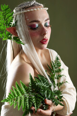 Naklejka premium Beautiful elf girl with floral decor on dark olive background