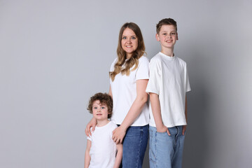 Fototapeta premium Portrait of mother and her sons on grey background, space for text