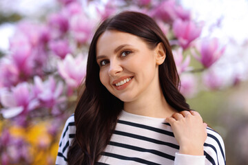 Fototapeta premium Beautiful woman in park with blossoming magnolia trees