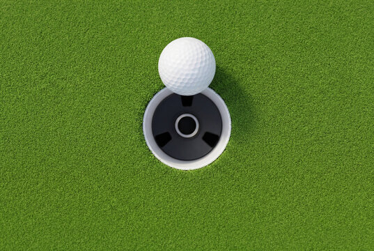 White golf ball resting right near hole on green grass