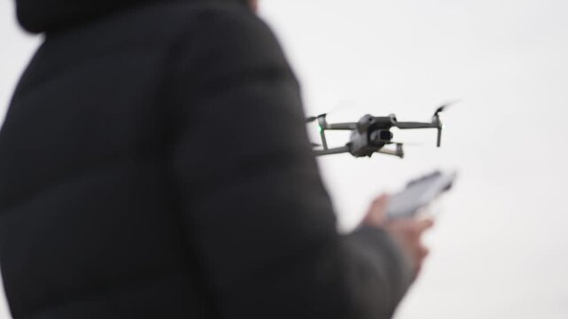 Drone operator using remote controller flying the quadcopter  above mountian lake