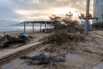 Obraz premium Debris litters a beach in Quy Nhon, Binh Dinh, Vietnam, after a storm. The aftermath shows damaged structures and scattered vegetation along the coastline.
