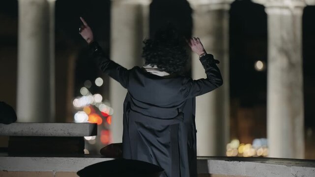 Stylish happy woman dancing with hands in the air onnight tour of Roman forum with background view of Tample of Saturn in Rome, Italy, slow motion