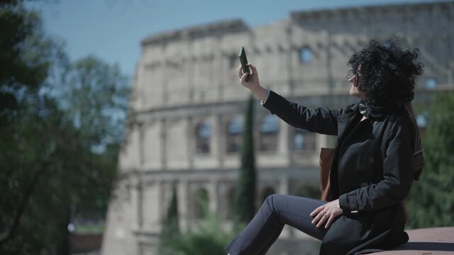 Happy young stylish business woman making selfie in front of colosseum in Rome, Italy, slow motion