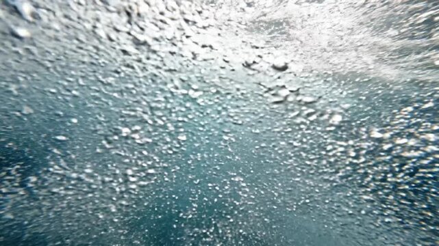 Slow motion underwater view of barrel waves captured in clear water at the beach during midday