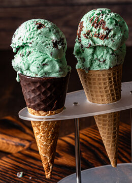 A close up of two mint chocolate chip ice cream cones in a stand.
