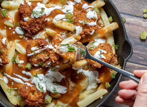 A close up look into a skillet of delicious homemade dill pickle poutine.